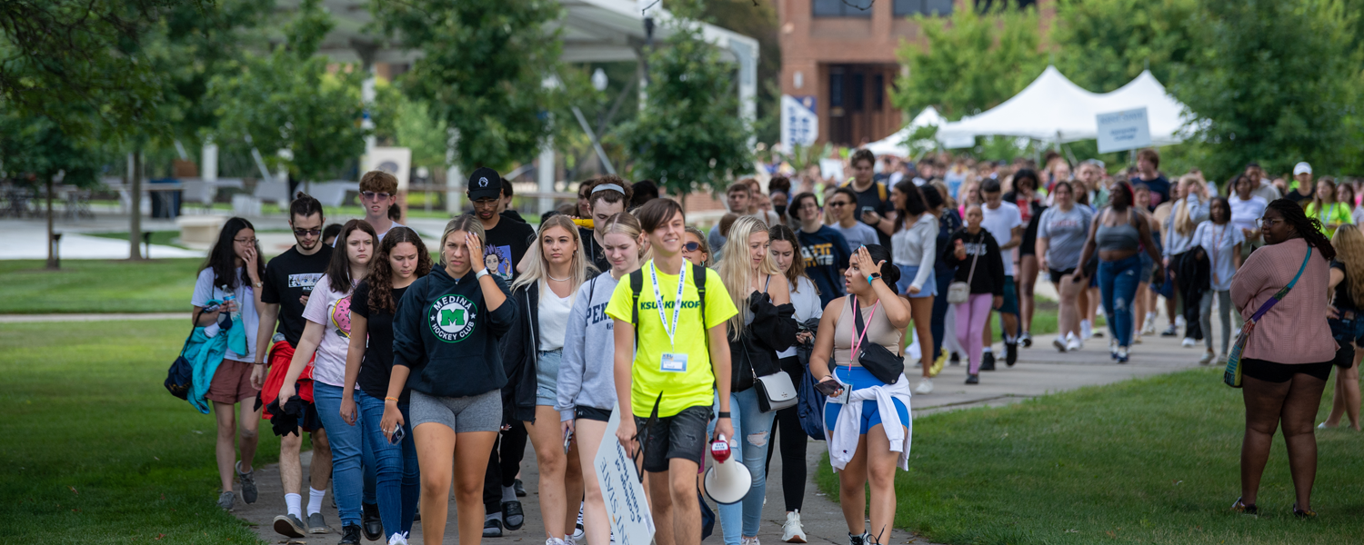 A large group of students are led on a tour across campus.