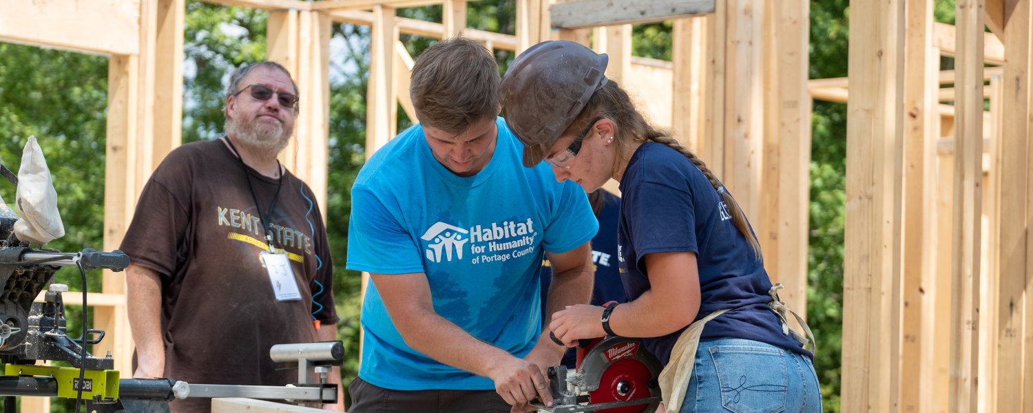 A student uses a circular saw at a Habitat for Humanity construction site as part of a volunteer event.