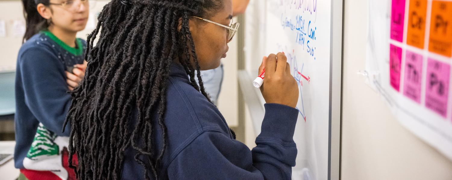 Students writing on markerboard