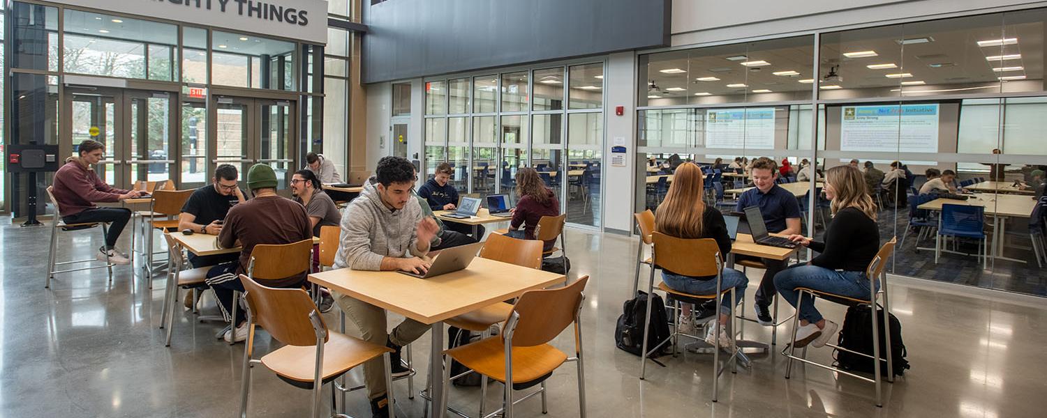 Inside the Aeronautics & Engineering building main atrium where several students are seated at raised tables.