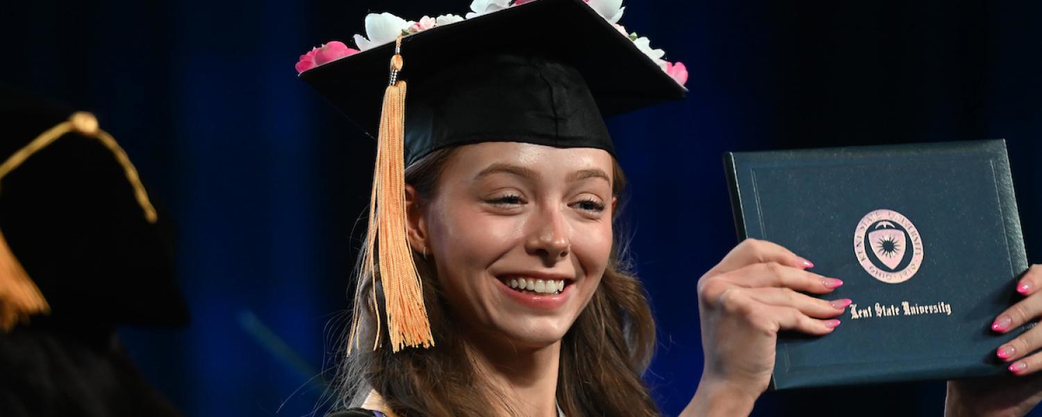 A new 91���� graduate proudly holds up her diploma during her commencement ceremony.