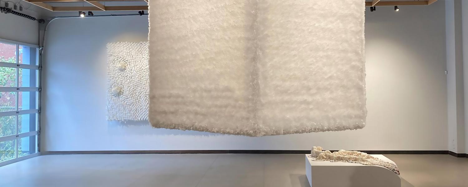 An art installation of a large textured cube suspended from the ceiling 