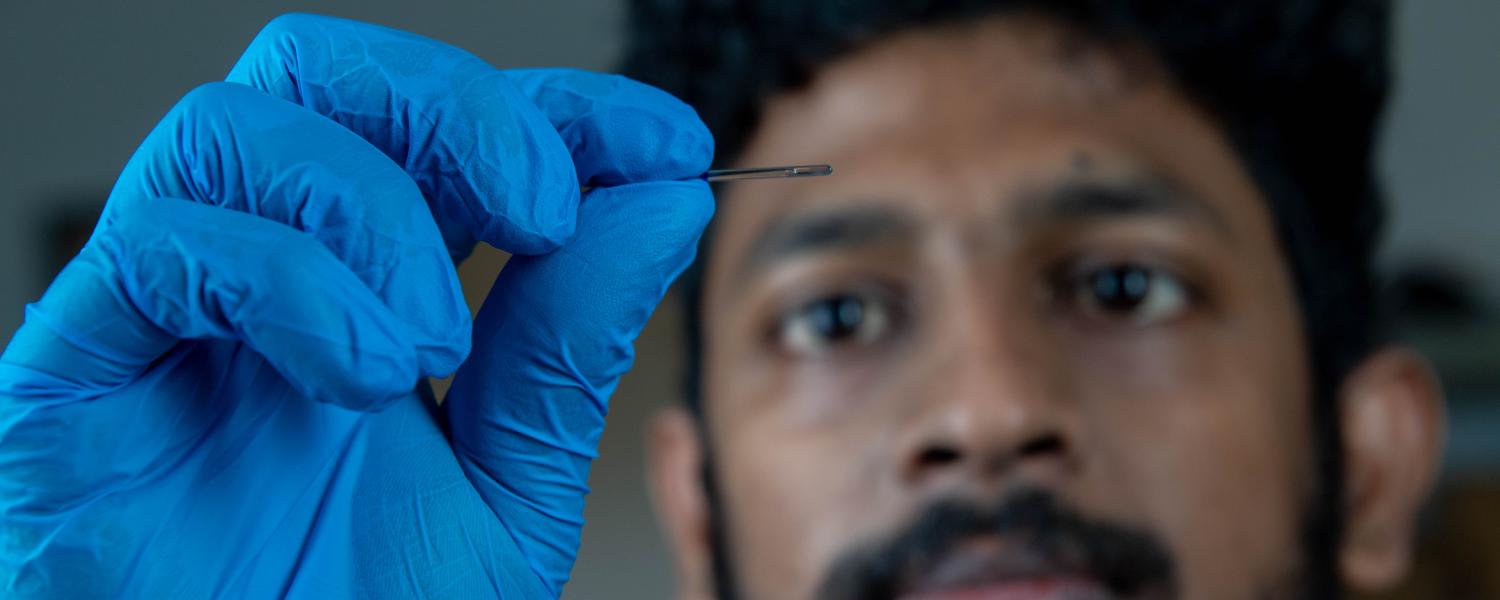 An image of a male student, wearing blue hand gloves, examining research findings