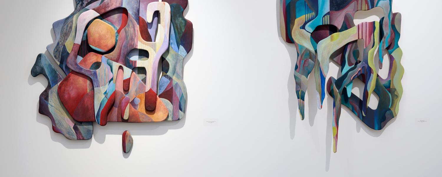 two colorful wooden sculptures on a gallery wall
