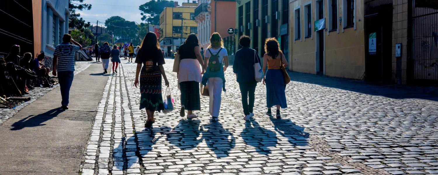 Five students walk down a stone road with their shadows cast by the sun.