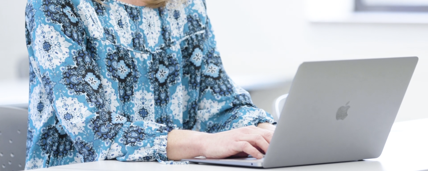 A Research, Measurement and Statistics doctoral student typing on an open Apple laptop.