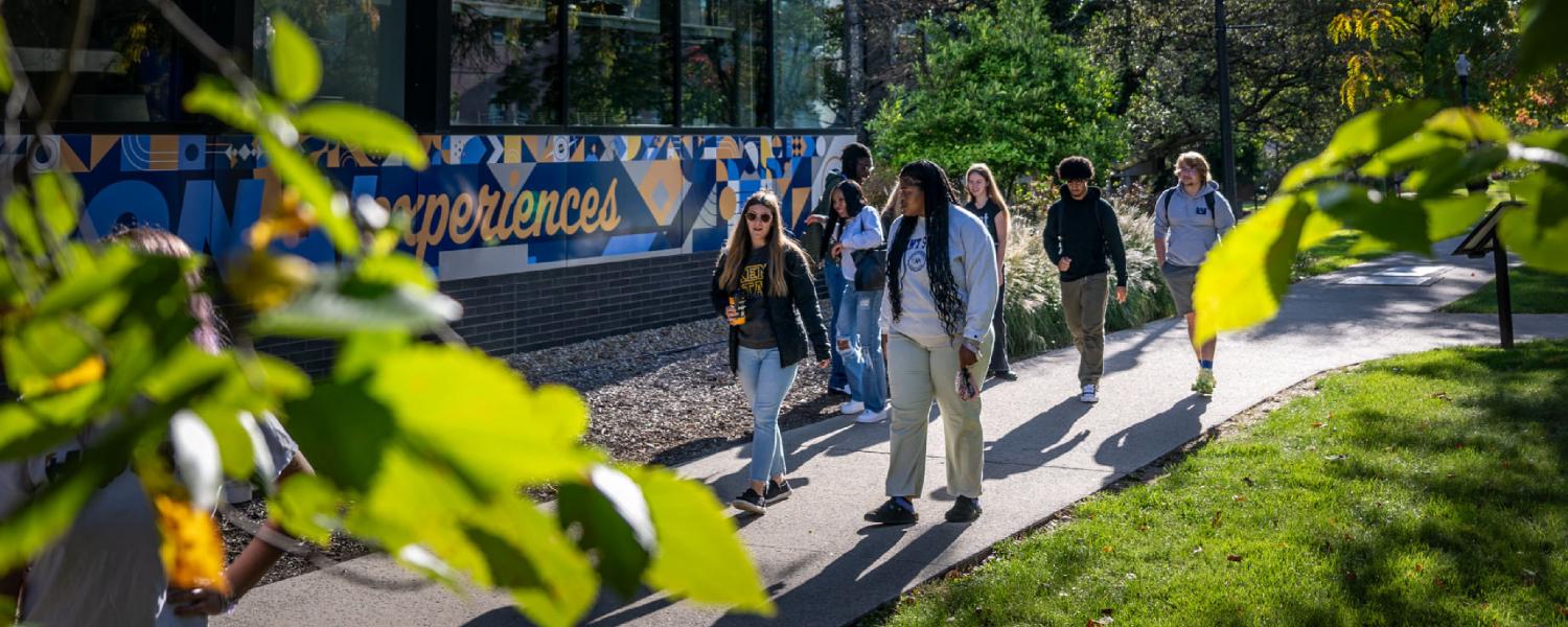 A group of students walking on campus on a sunny day.