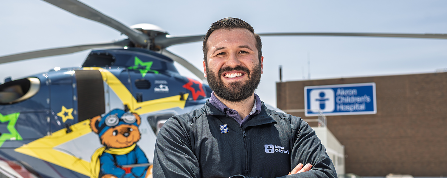 Teddy Pavlantos poses in front of a helicopter on the roof of Akron Children's Hospital