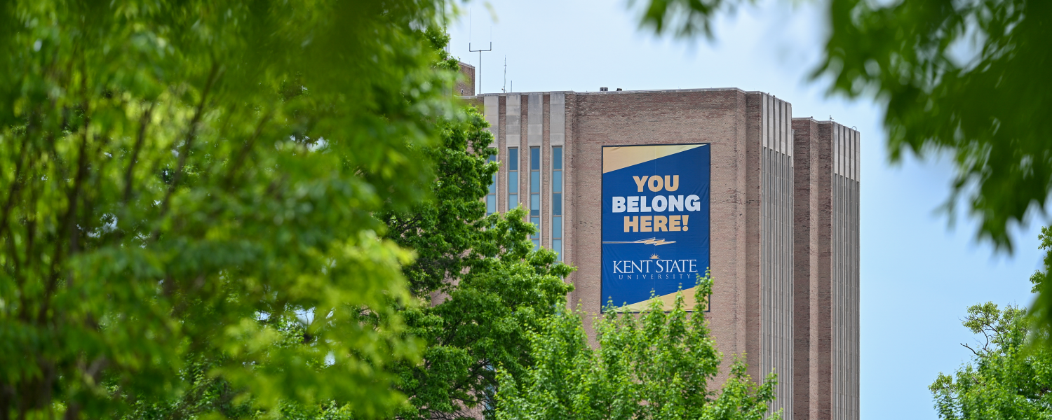 The Kent State library framed by lush green trees.