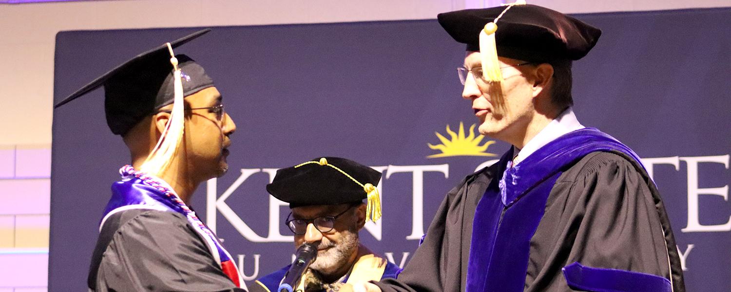 Dean Bill Ayres shakes the hand of a graduating student at commencement