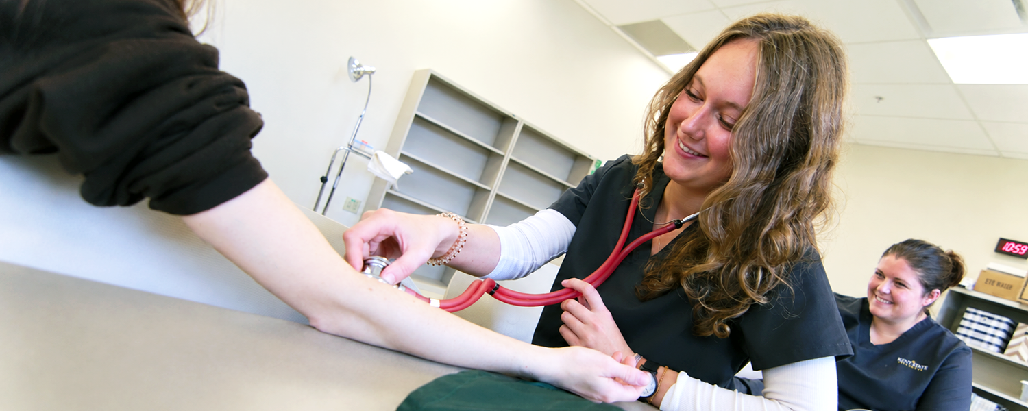 A medical assisting student takes the blood pressure of a classmate