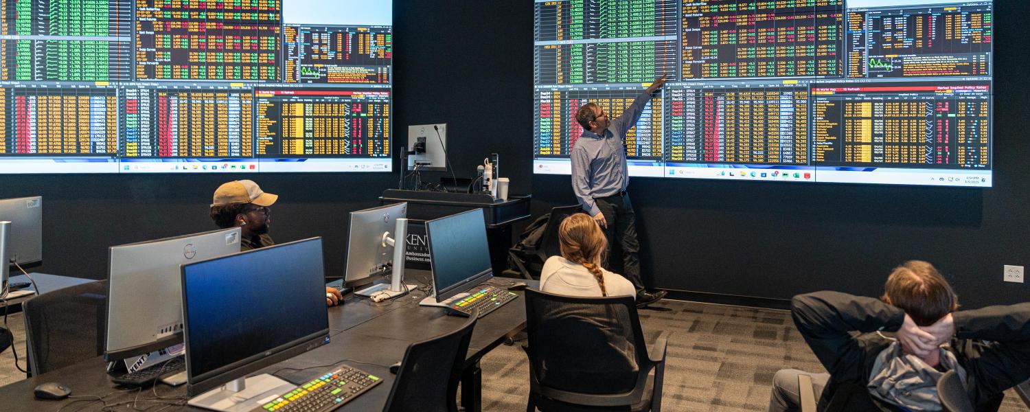 professor giving a lecture in the finance trading floor lab.