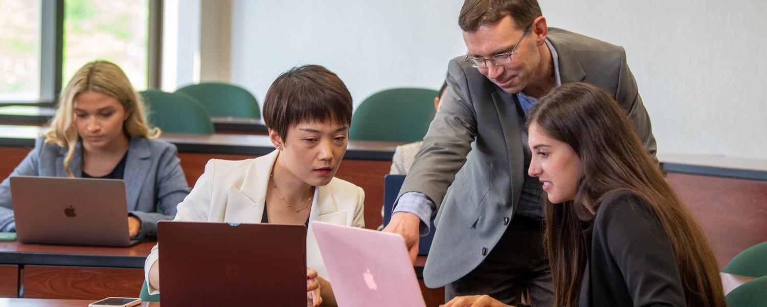 professor shows students something on laptop