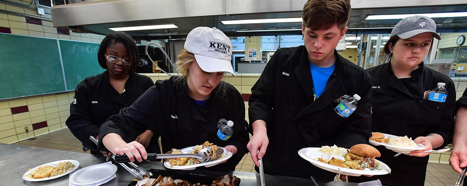 Hospitality students serving and plating food. 