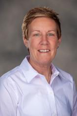 Professional headshot of Missy Hatch wearing a light-colored collared shirt against a neutral gray background.