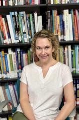 Julee Henry, director of the IRC, in a white top, the background is a library with book shelves.