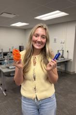 Lilly McKinney in a yellow shirt holding 3D printed math manipulatives