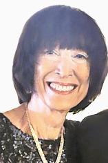 A smiling woman with dark hair wearing a black sequined top and a gold necklace.