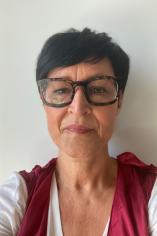 Headshot of Silvia, her hair dark and close-cropped to her ears. She wears large, square dark brown glasses