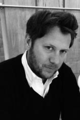 A black and white photo of a man with dark hair and a light beard