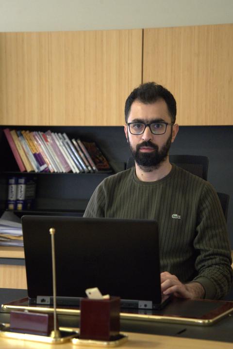 An Image of Harem Majeed sitting in an office working on a laptop
