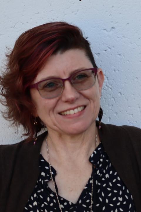 photo of smiling woman with glasses against a white concrete background