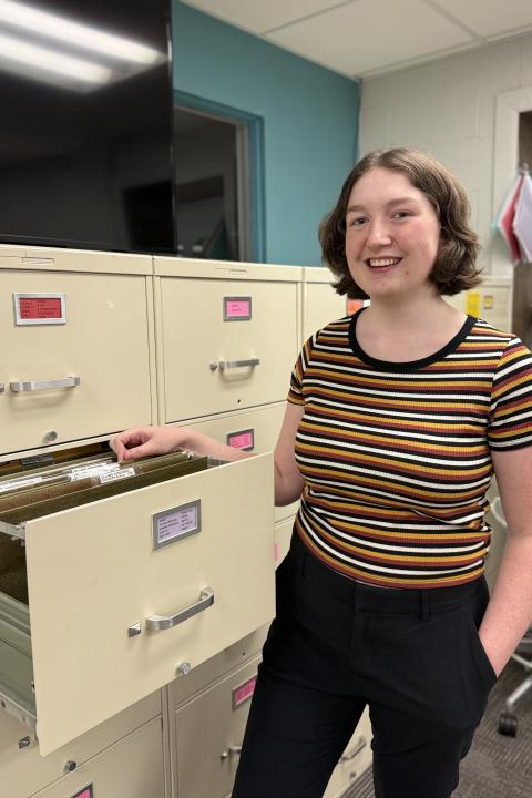 Katie Kleinfelter posing for a picture opening a filing cabinet.