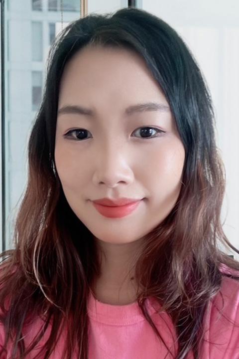 A woman in a pink top with dark hair smiles at camera