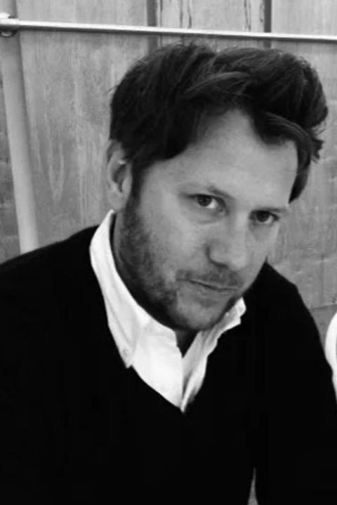 A black and white photo of a man with dark hair and a light beard