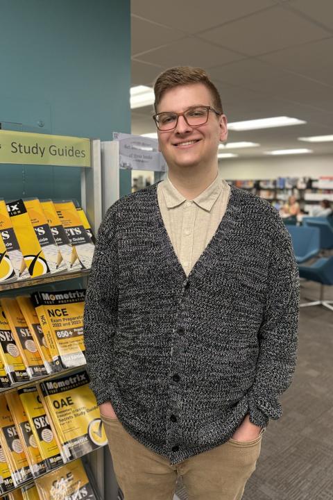 Zach Fediaczko standing next to yellow OAE study guide books.