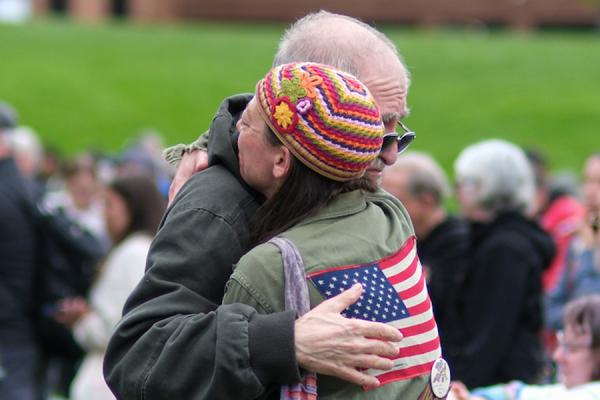 Friends hug while members of the Kent State University community and visitors gather on the Kent State Commons for the annual May 4 Commemoration to honor those who were killed and wounded on May 4, 1970. (Photo credit: Bob Christy, Kent State University)
