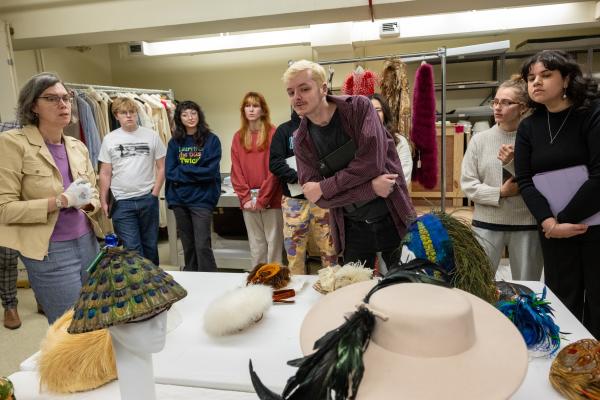 Group of students gathered around a table looking at feathered hats