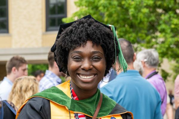 A woman smiles wearing graduation regalia.