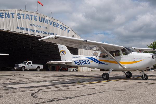 A single-engine airplane parked outside a hangar.