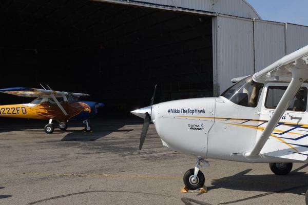 Two airplanes parked outside the Kent State Airport Hangar.