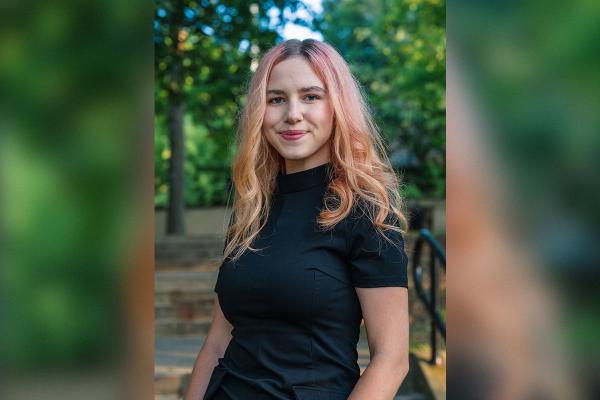 Female student with pink hair among trees