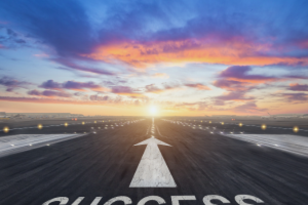 The word "success" on a road, with an arrow pointing towards the horizon.