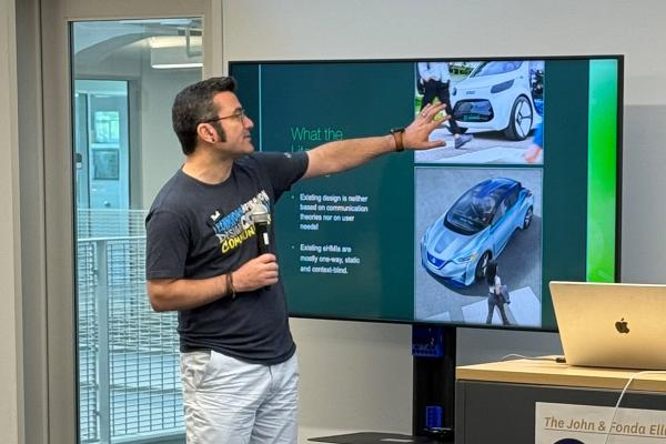 Design Innovation Fellow Hadi Rahmati points to large monitor and explains autonomous car feedback