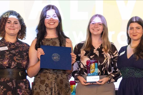 Two students accepting an award, event staff on both sides