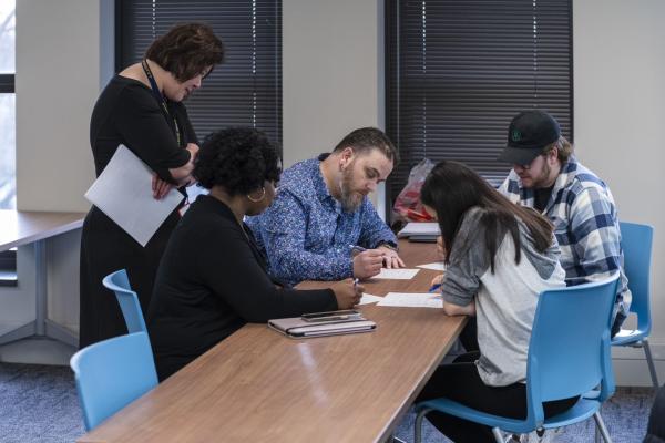 A group of EMAT students and their instructor reviewing a group project they are working on