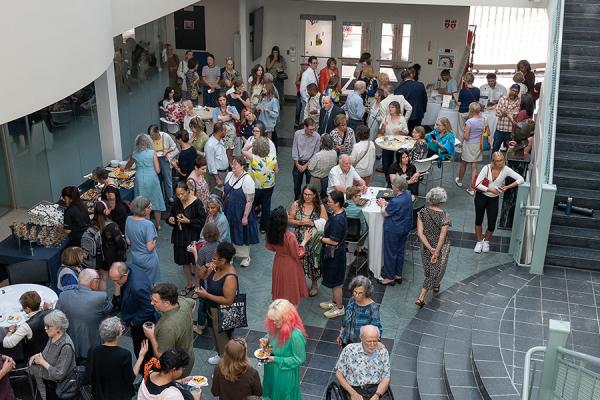 A large group of people stand in the atrium of Rockwell Hall during the opening reception for the “Every Last Scrap” exhibition at the Kent State University Museum.