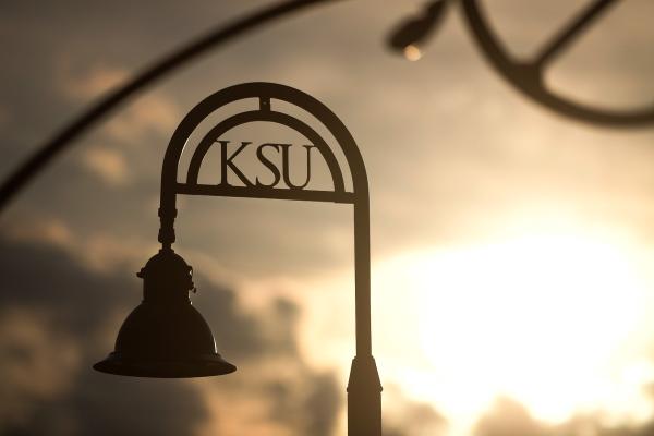 A close up of a KSU lamppost against a cloudy sky.