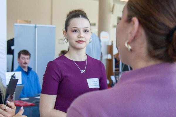 Students smiling and talking with recruiter.