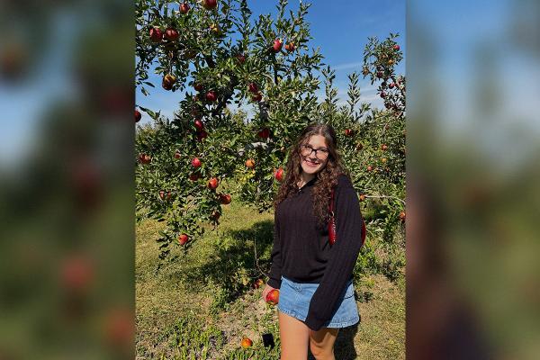 Woman standing in front of apple tree in orchard