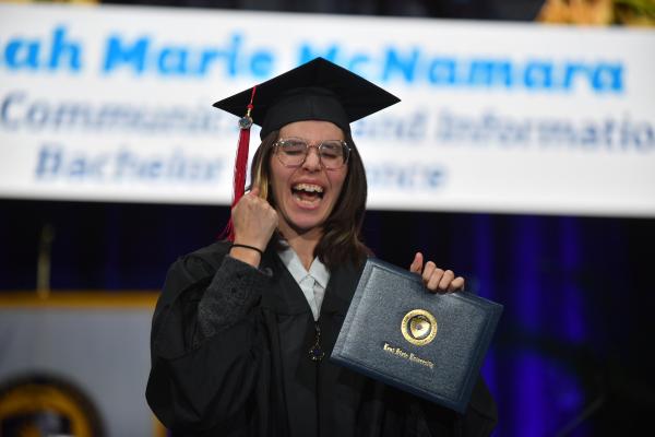 A new graduate celebrates walking across the stage during fall 2025 commencement ceremonies