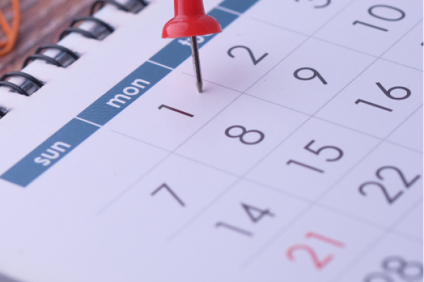 Close up of a calendar with a red push pin on the first of the month