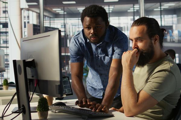 A man helps another man at a computer