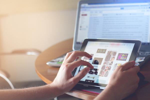 A pair of hands holding and using a tablet device.