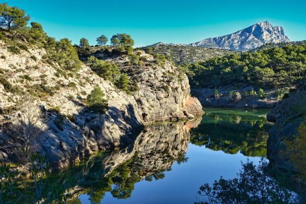 Landscape mountain rocks over lake, blue sky, reflection and green trees, France.