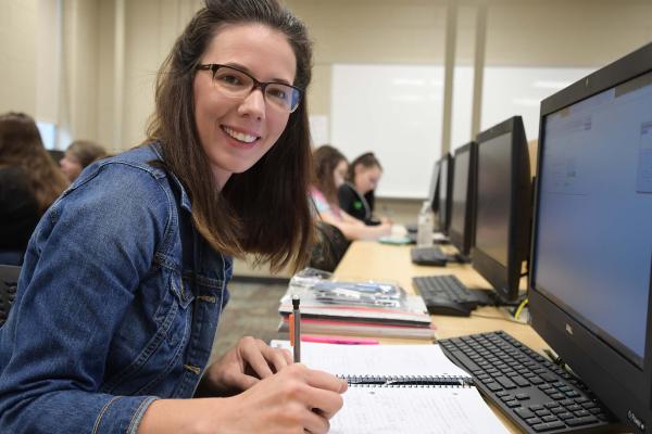 Woman writing in front of computer